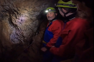 72 year old Steve kitted up to go caving for nature wearing overalls, head torch and helmet just inside the cave entrance