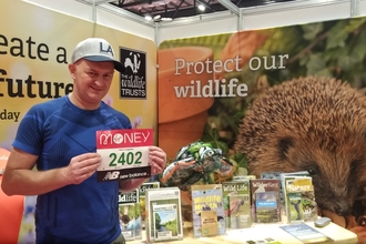 London Marathon runner holding his race number onfront of a Wildlife Trusts display