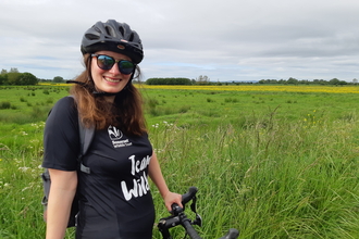 Smiling cyclist stopped in front of views across the somerset levels