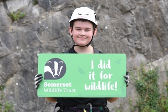 Abseiler holding a sign saying "I did it for wildlife!"