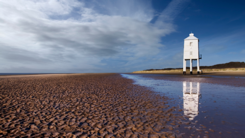 Landscape picture of Burnham-on-Sea beach on sunny day with lighthouse in background