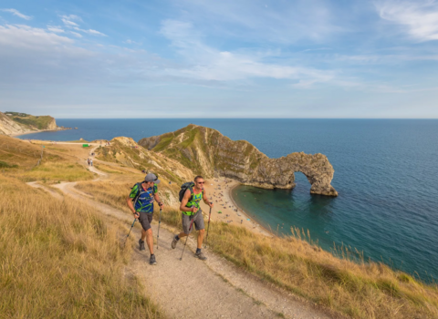 Two walkers on the south west coast path with Durdle Door in the background